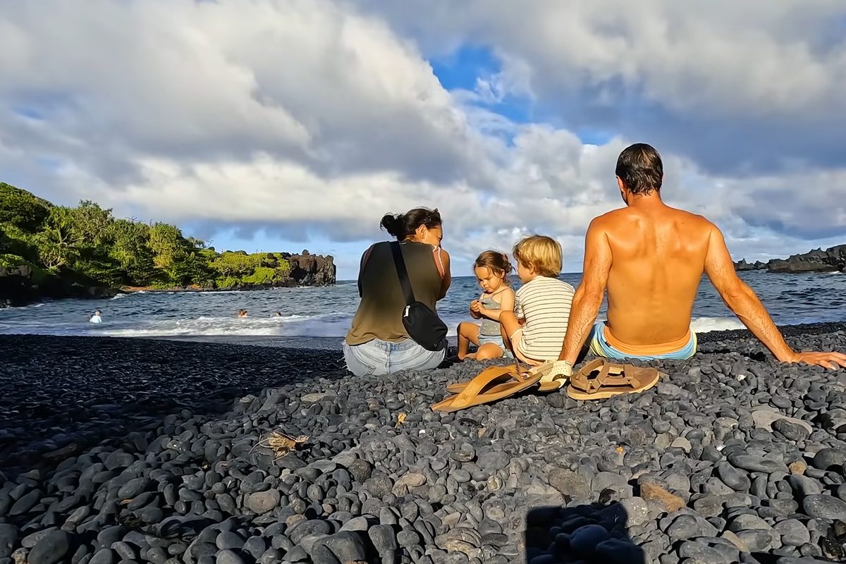A family sitting on a black sand beach