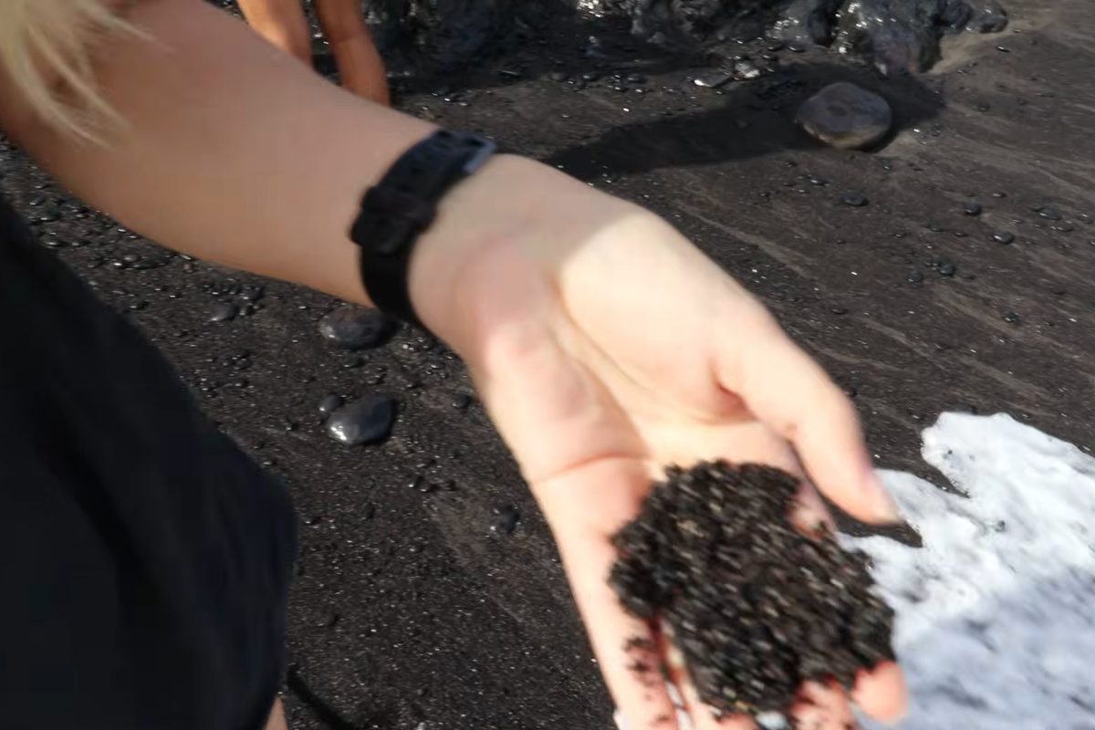 Black sand in the palm of a hand