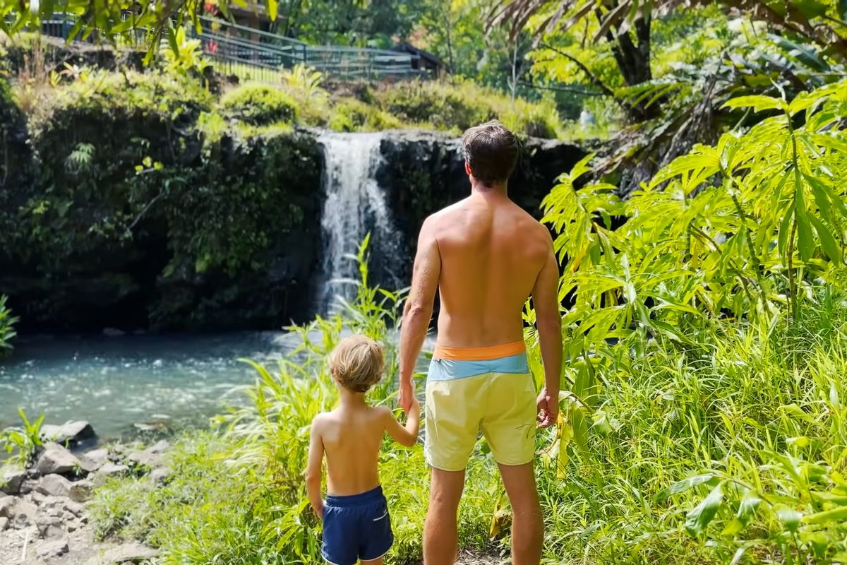 Father and son looking up at a waterfall on the Road to Hana