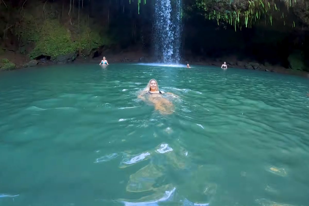 Swimmers in a turquoise waterfall pool
