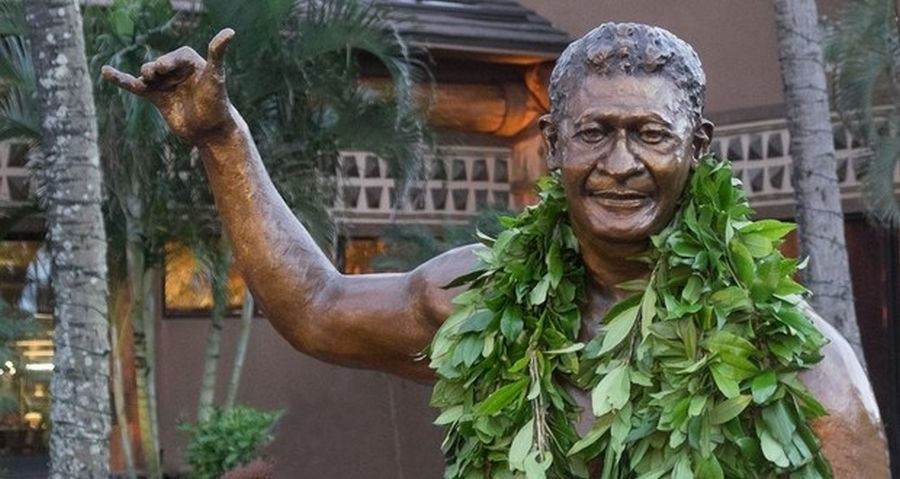 Bronze statue throwing a shaka, wearing a maile lei