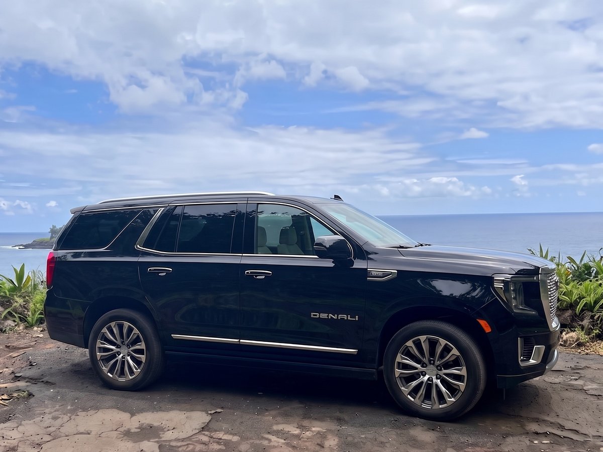 Black GMC Yukon Denali parked at a coastal pullout above the ocean